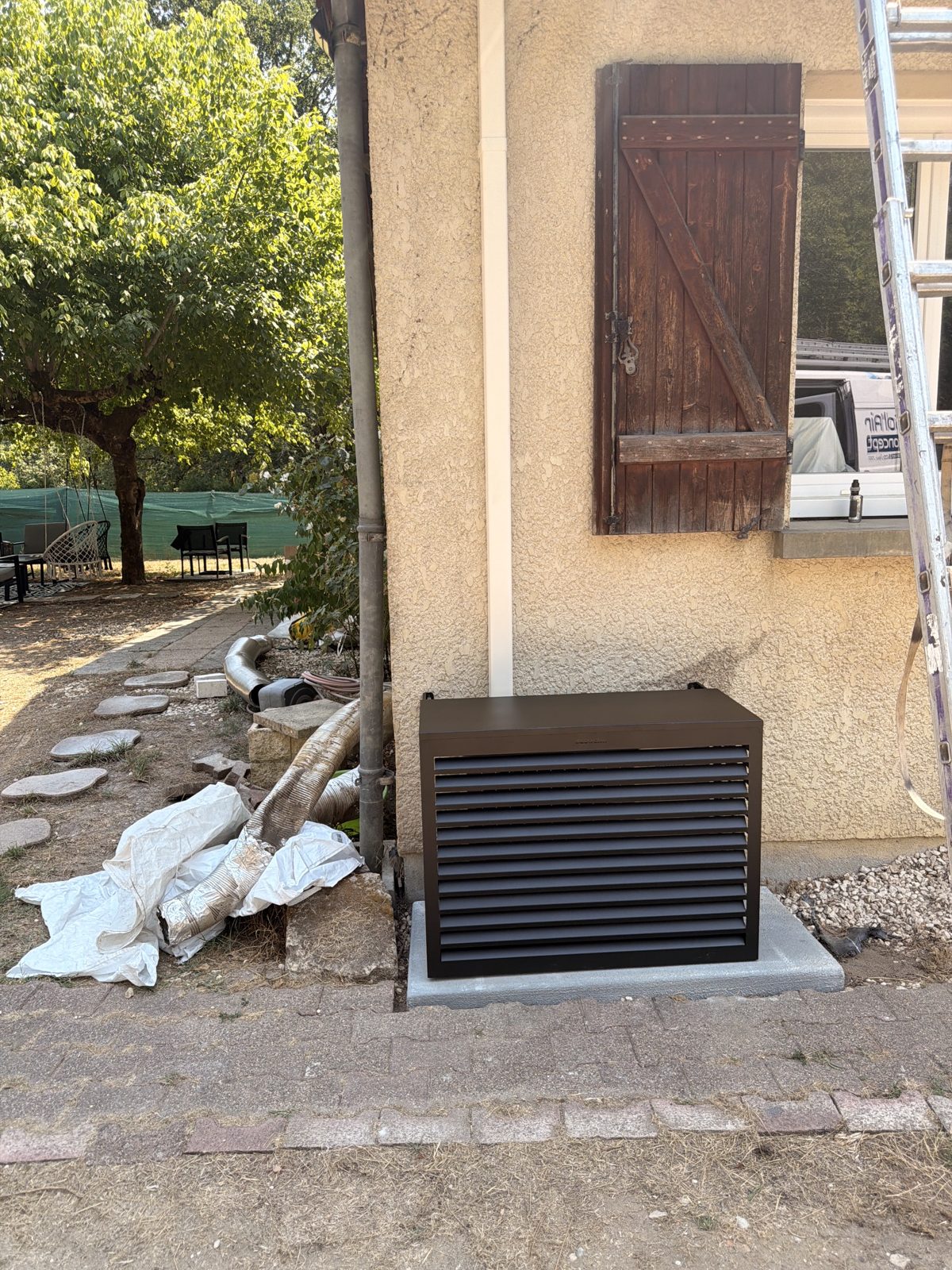 Groupe extérieur de pompe à chaleur habillé d'un cache design sur dalle béton