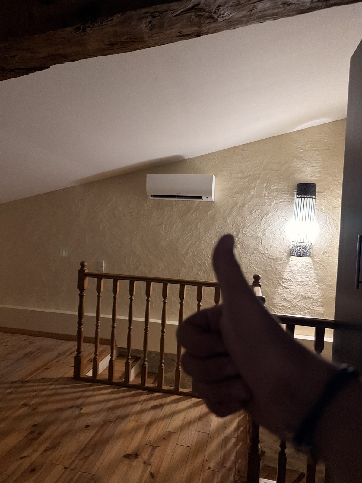 Split mural de climatisation posé sous rampant dans une maison en pierre